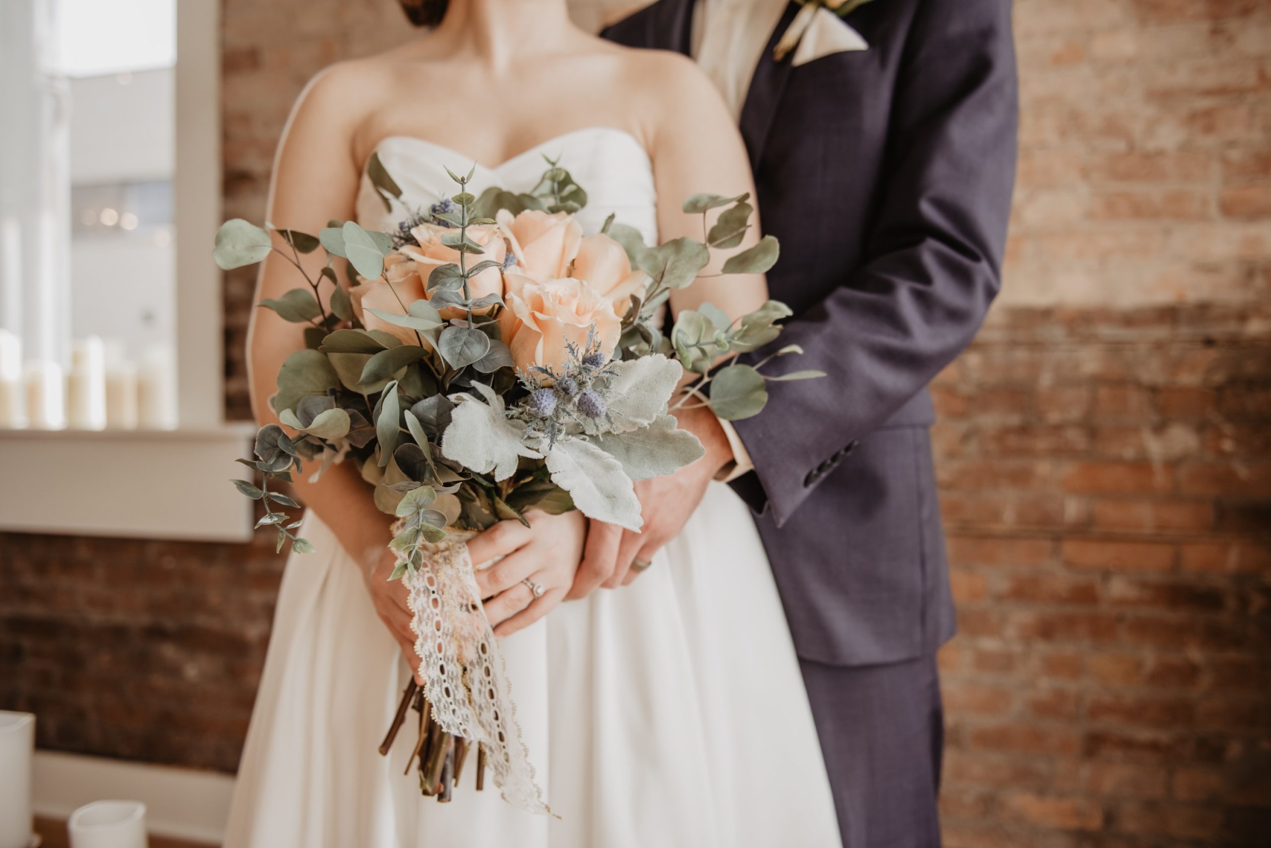 couple on their wedding day with green and peach flowers